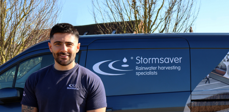 a commissioning engineer for rainwater harvesting and greywater recycling systems in the UK next to a van.